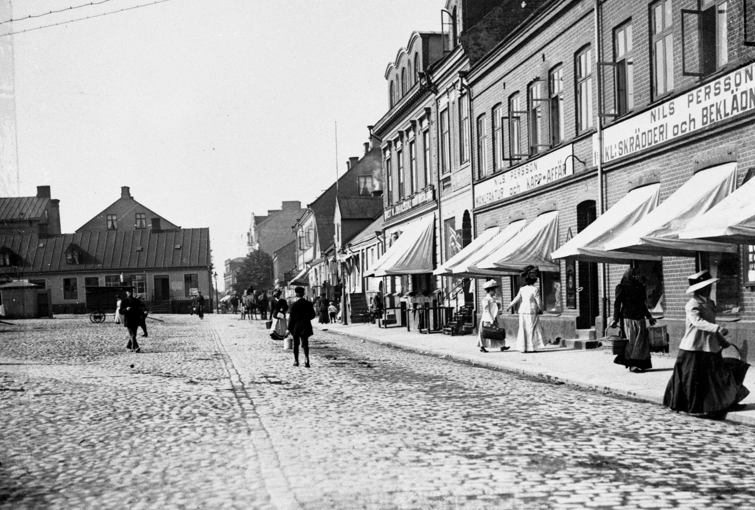 Tidigt 1900-tal. Fotot &auml;r taget mot v&auml;stra sidan, l&auml;ngs med S&ouml;dergatan. M&aring;nga av husen p&aring; fotot &auml;r nu rivna. En del eleganta damer h&auml;r! K&auml;lla: Esl&ouml;vs kommuns bildarkiv, F&ouml;jers foto.