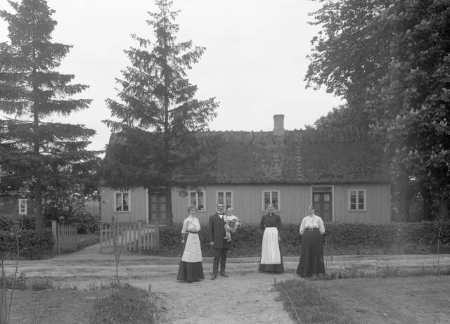 Fru Olsson, Reslöv. Familj samlad framför boningshuset. Källa: Eslövs kommuns bildarkiv, Föjers foto.