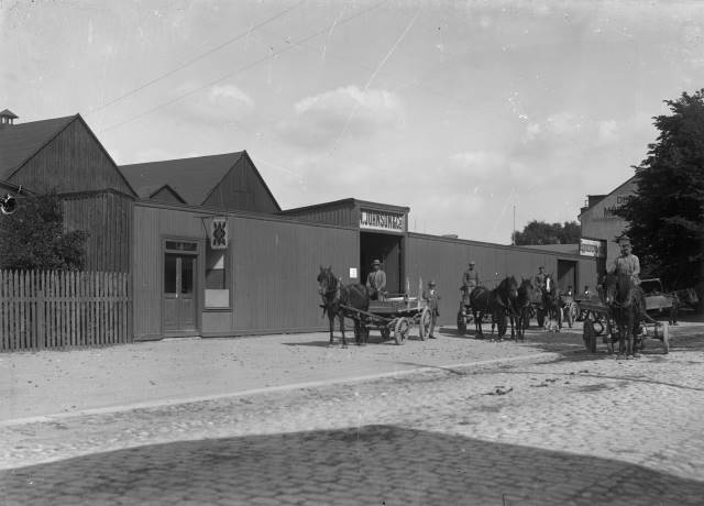 Hästdragna vagnar utanför Johnson & Co. Östergatan mittför gamla Östra Skolan, idag Carl Engströmskolan. Föjers arkiv.