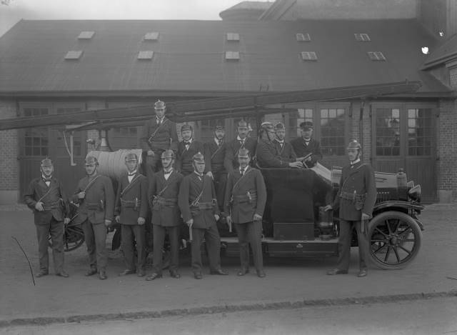 Eslövs första brandbil inköptes 1920. Här med brandmän ståendes framför brandstationen i hörnet Villavägen-Södergatan. Föjers arkiv.